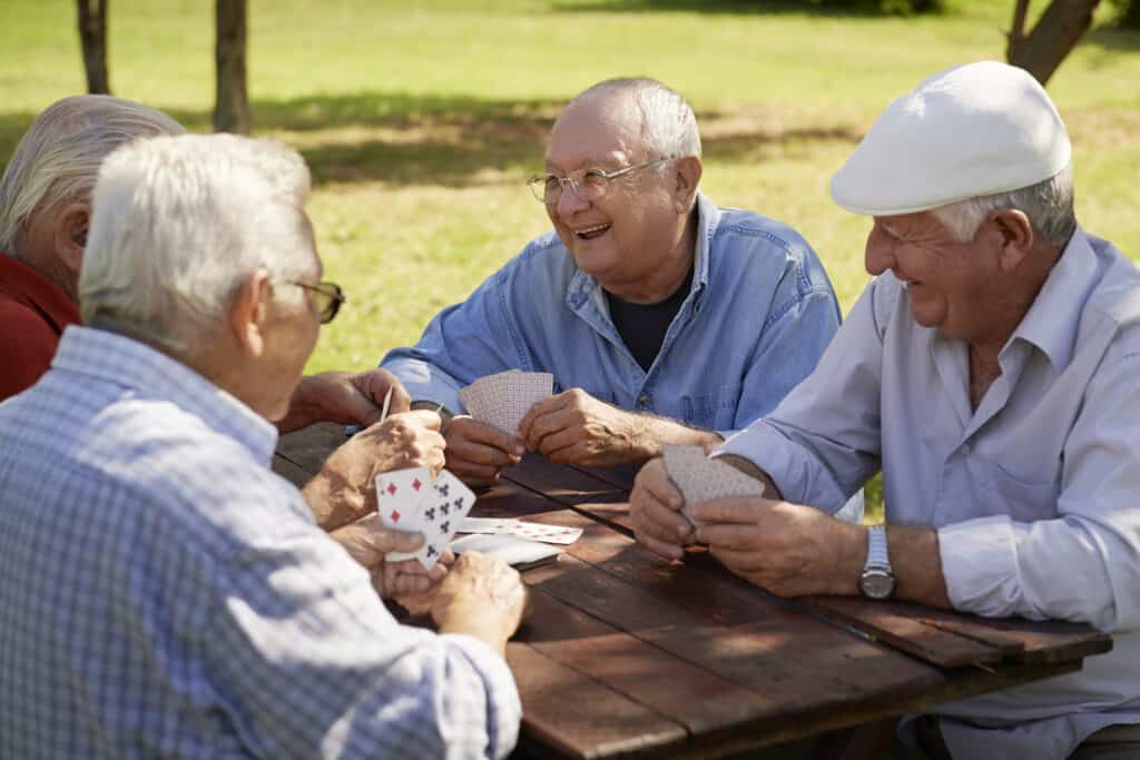 Group of senior men, smiling and playing cards at the park men's social group
